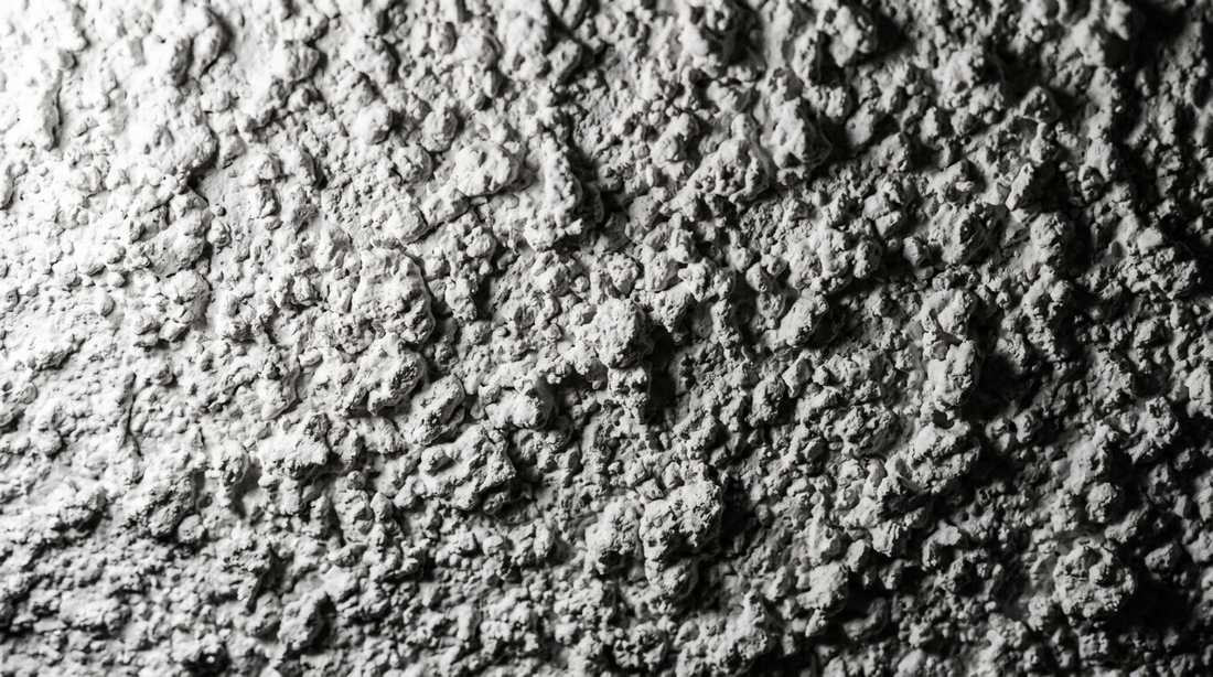 Close-up of white sprayed acoustic popcorn ceiling texture in raking light